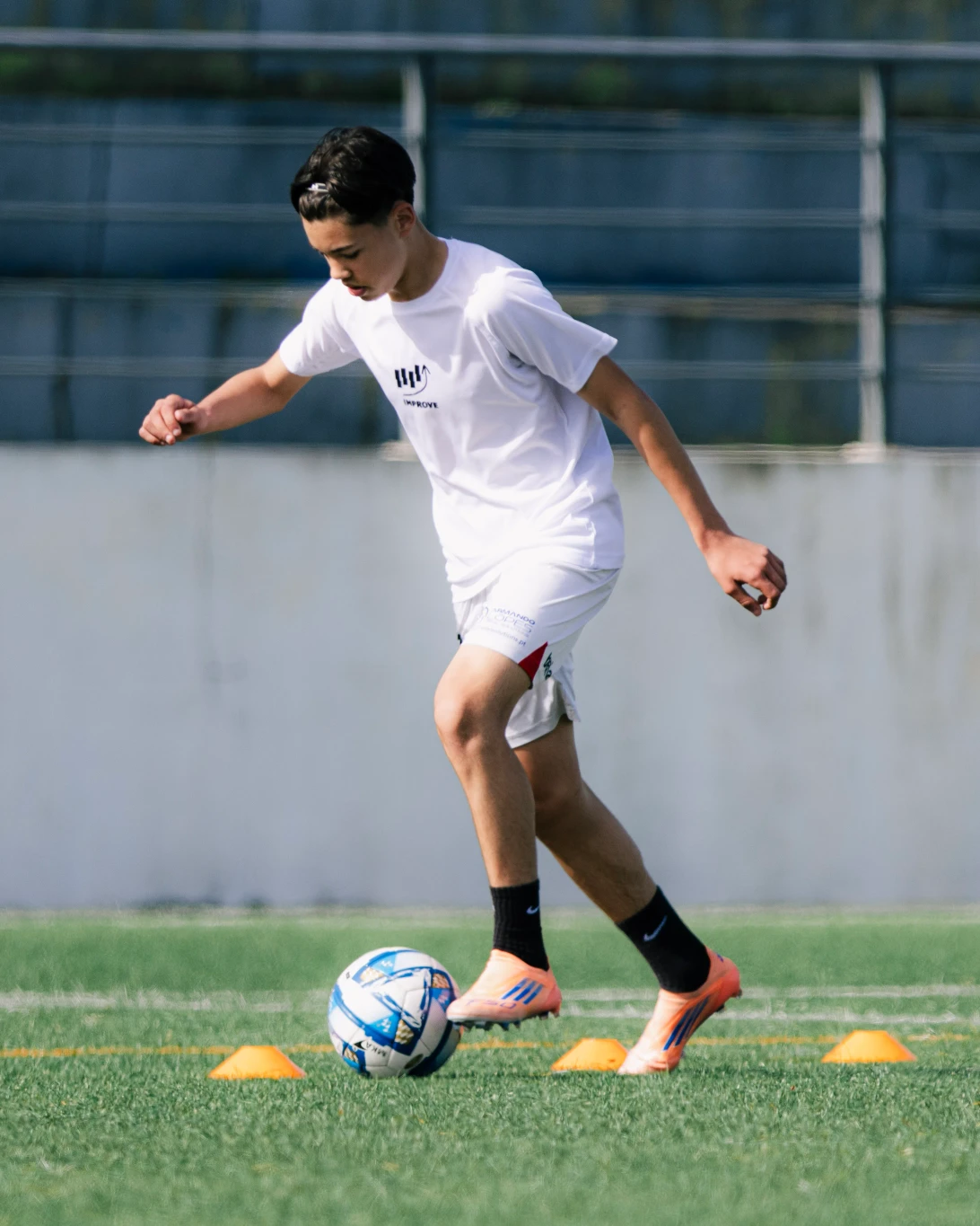 Atleta a conduzir a bola entre cones num treino Improve