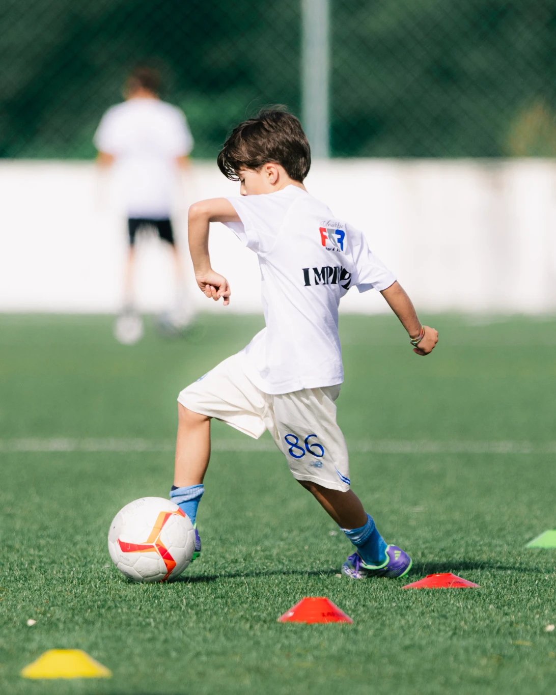 Jovem atleta a driblar com a bola num treino Improve